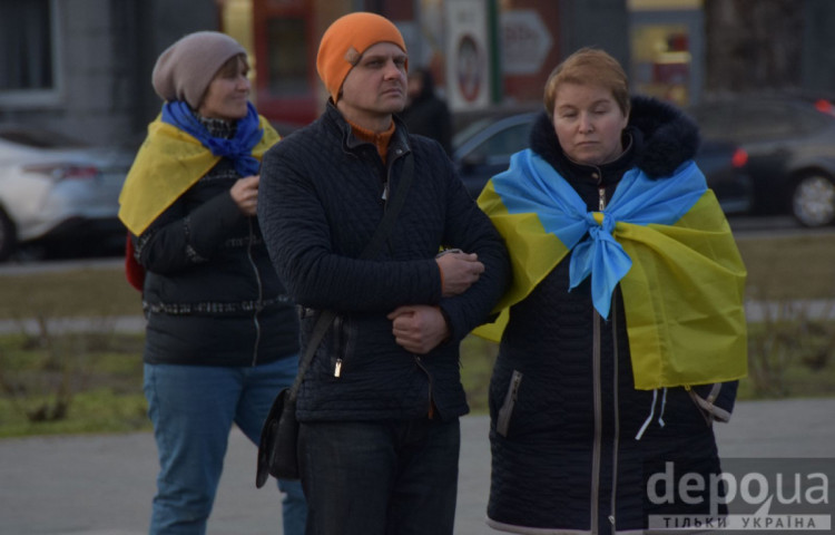 Люди, обгорнуті жовто синіми прапорами